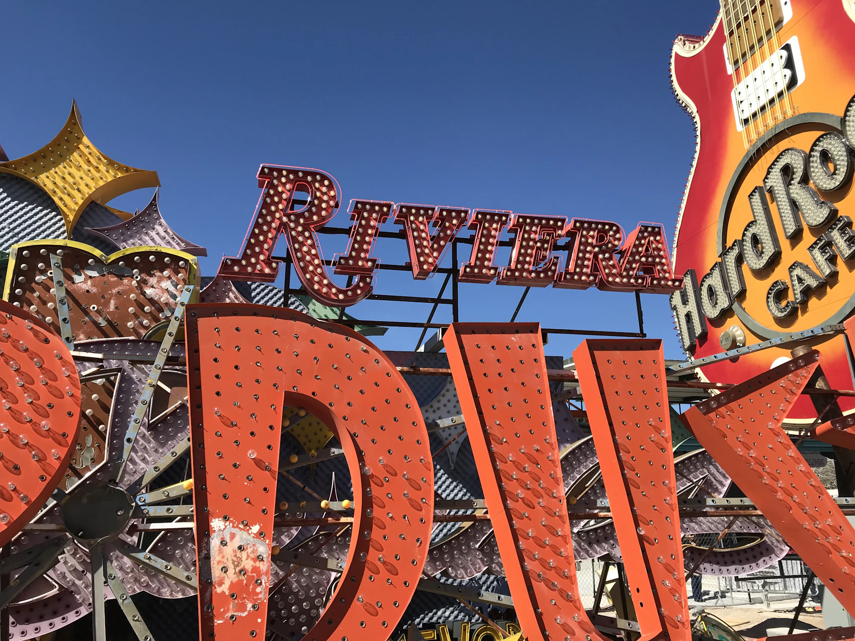 Historic neon casino signs arranged outdoors against a clear blue sky