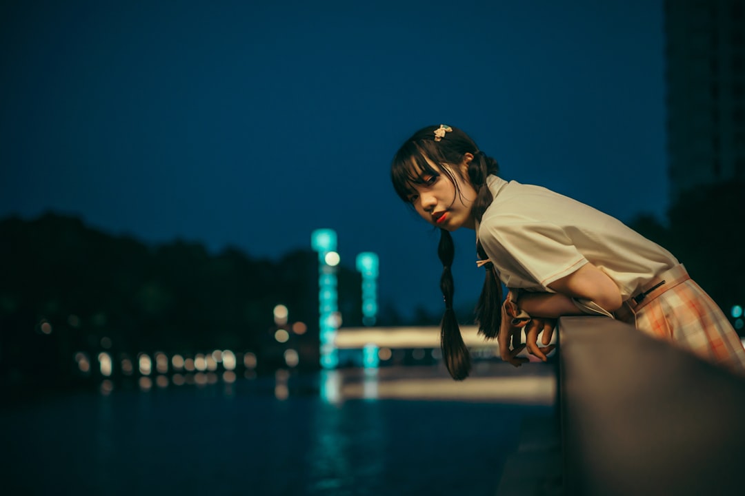 woman in white long sleeve shirt standing near body of water during night time