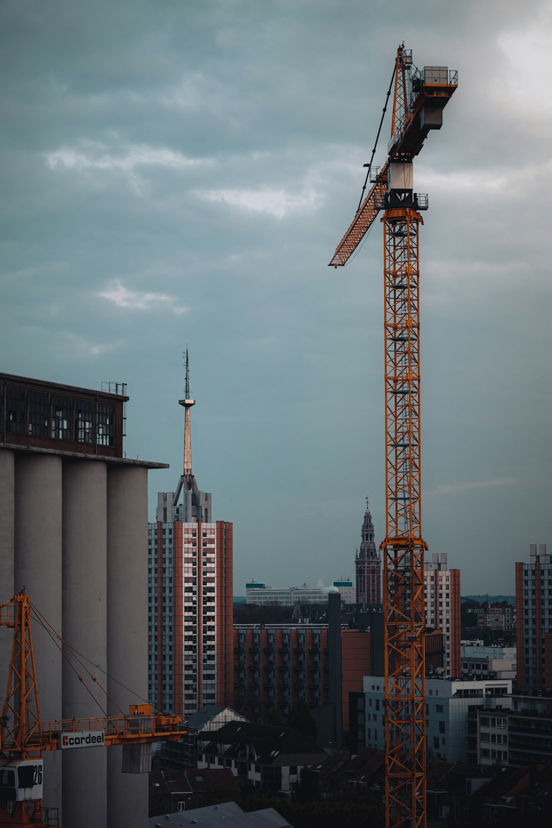 orange tower crane near city buildings during daytime
