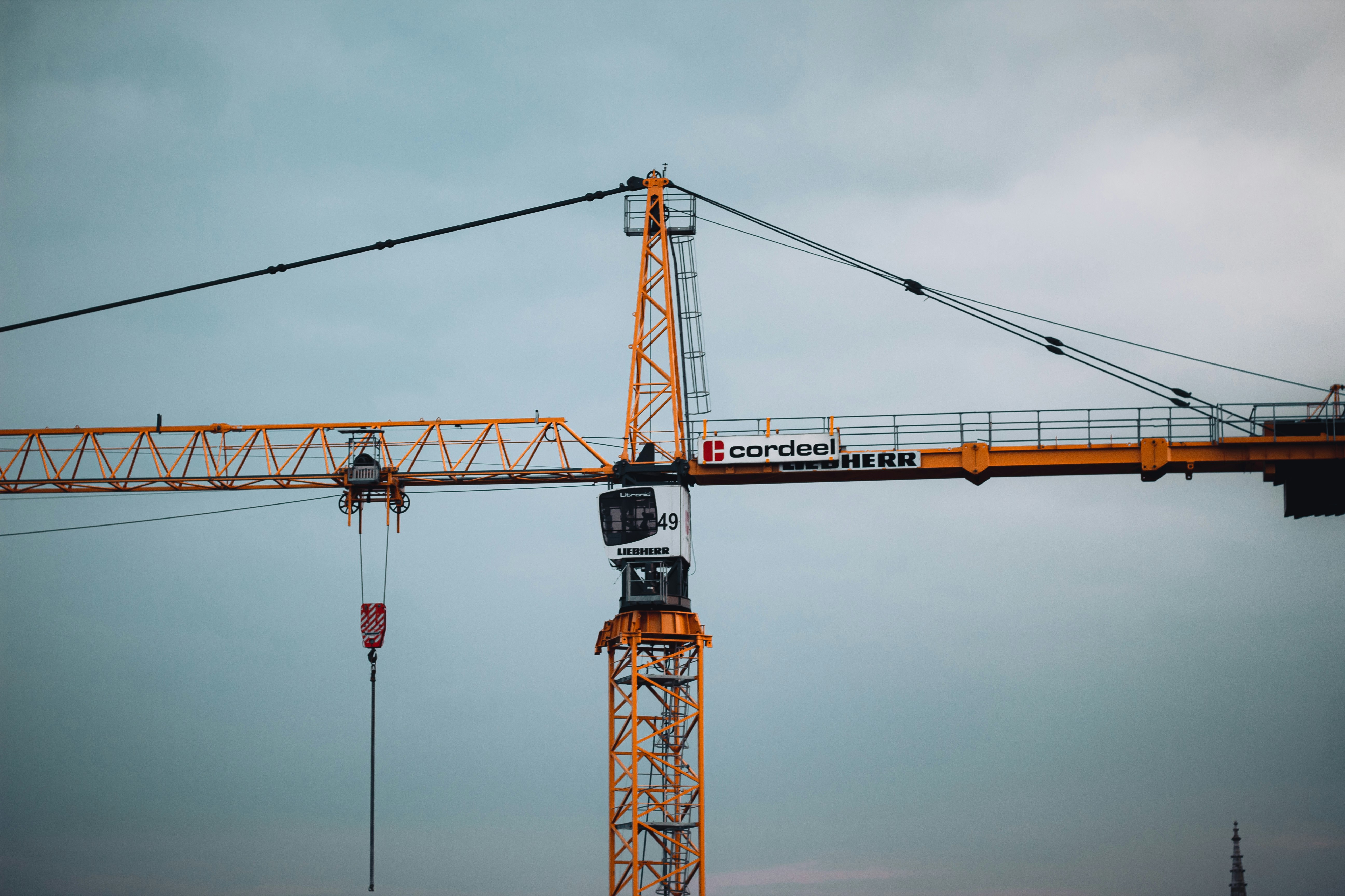 orange and black tower crane under gray sky