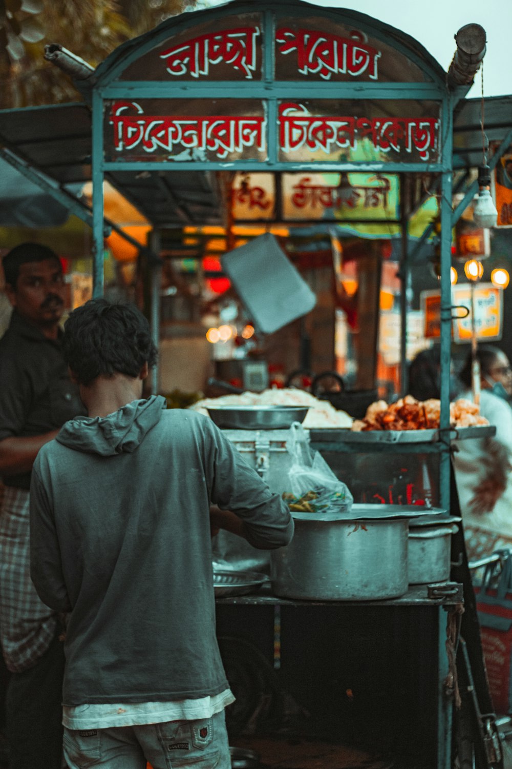 man in gray jacket standing in front of food stall during daytime