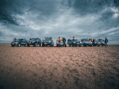 black suv on brown sand under cloudy sky during daytime
