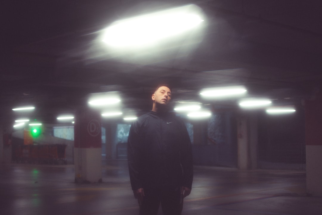 man in black jacket standing on gray concrete floor