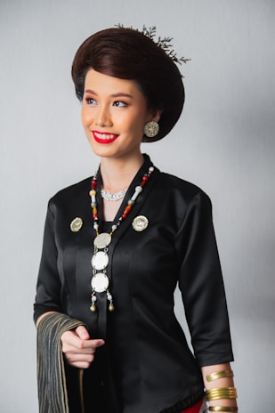A smiling woman wearing elegant earrings and rings from Likha Trinkets, standing against a soft, natural background.