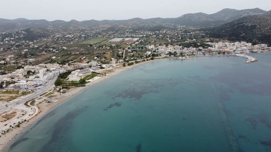 A coastal town from the air, low white building spreading back from the bay into the hills.