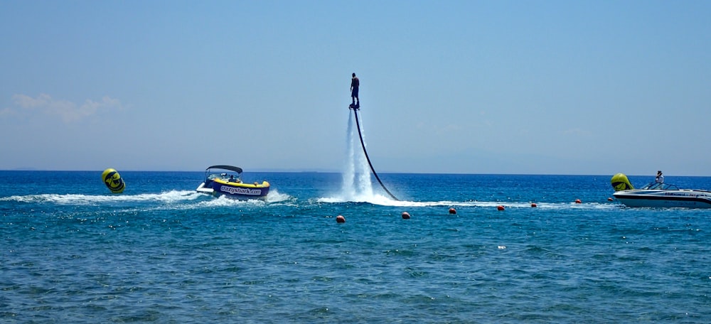 person in black wet suit riding yellow and white personal watercraft on sea during daytime