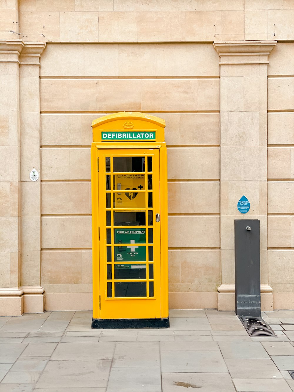 ベージュのコンクリートの建物の横にある黄色い電話ボックス