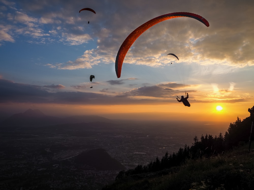 silhouette of people riding parachute during sunset
