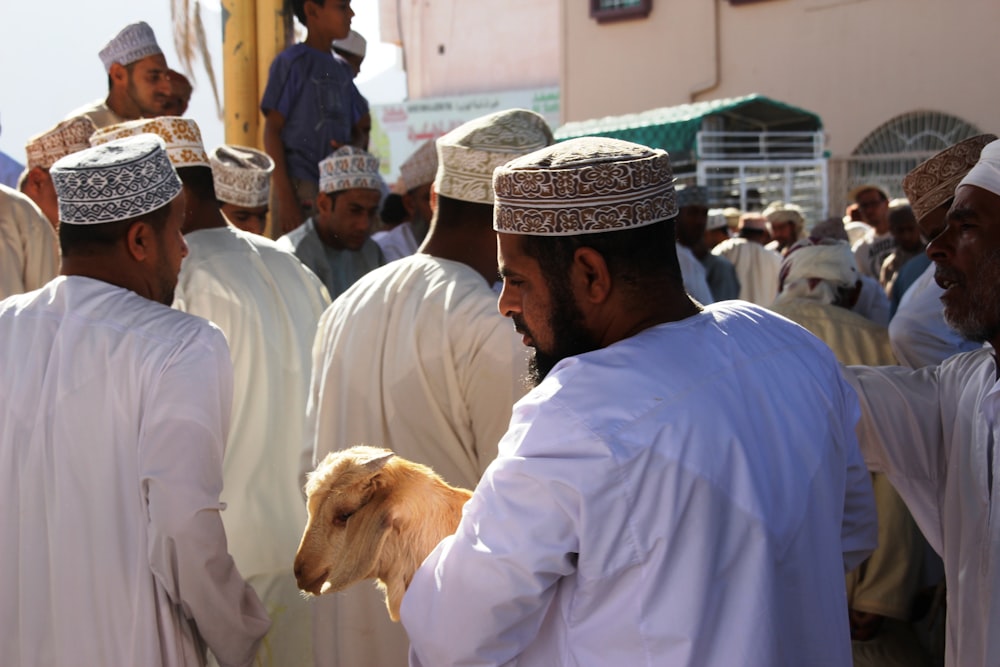 man in white dress shirt and brown hat standing beside white short coated dog during daytime