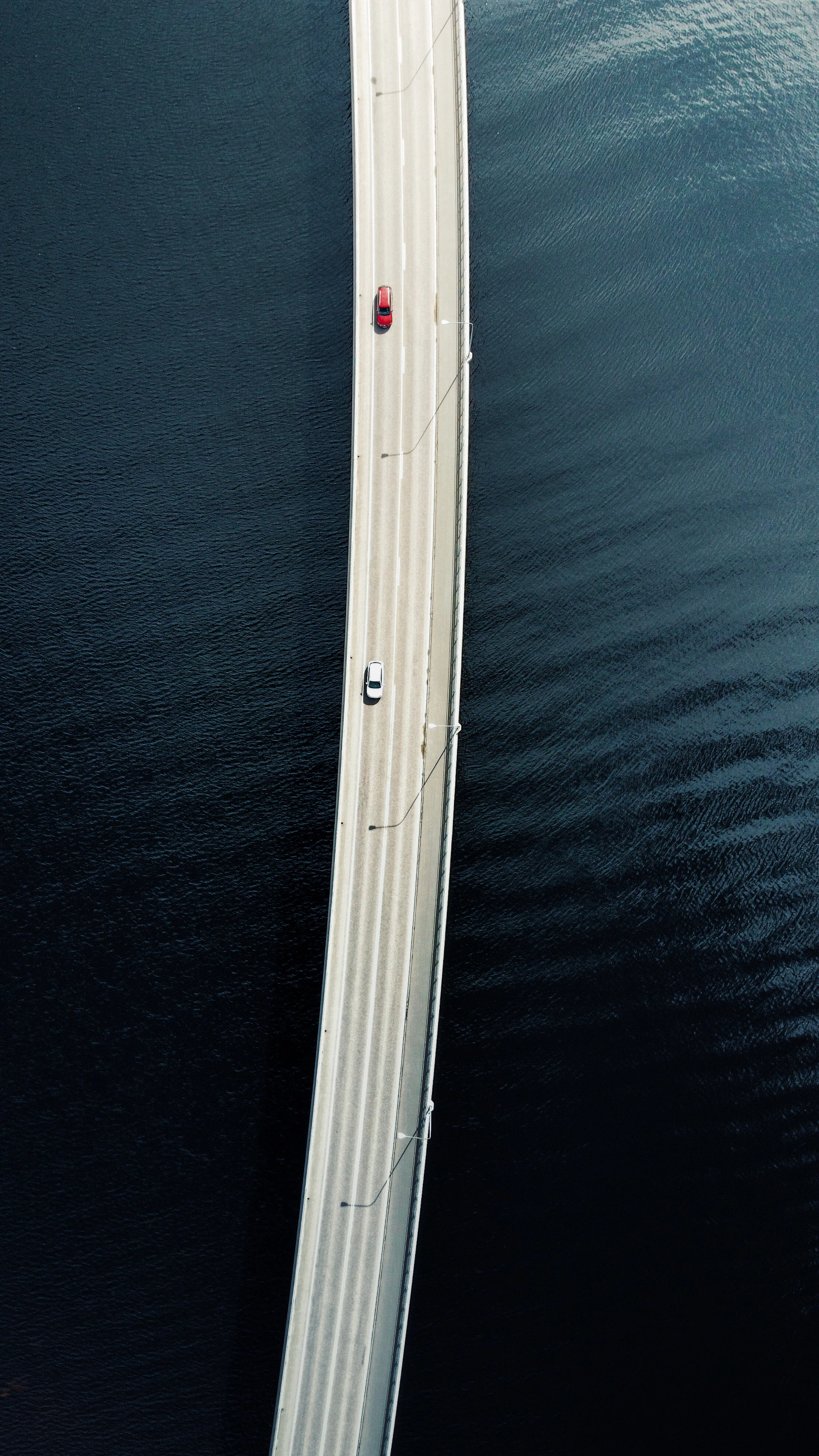 Car crossing a narrow bridge over a Finnish lake