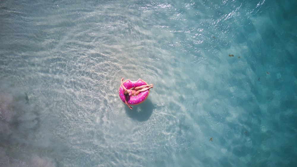 person in pink kayak on body of water during daytime