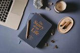 a book titled "The Story of My Life" is sitting on top of a table next to a laptop