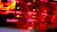 A close-up view of a server room or data center with bright red LED lights. The lights form various technical terms, suggesting network or server activity. The background is dark, highlighting the vibrant, dynamic lines and letters.