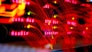A close-up view of a server room or data center with bright red LED lights. The lights form various technical terms, suggesting network or server activity. The background is dark, highlighting the vibrant, dynamic lines and letters.
