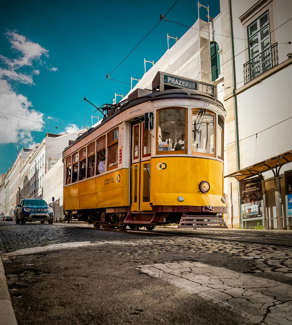 yellow and white tram on road near white concrete building during daytime