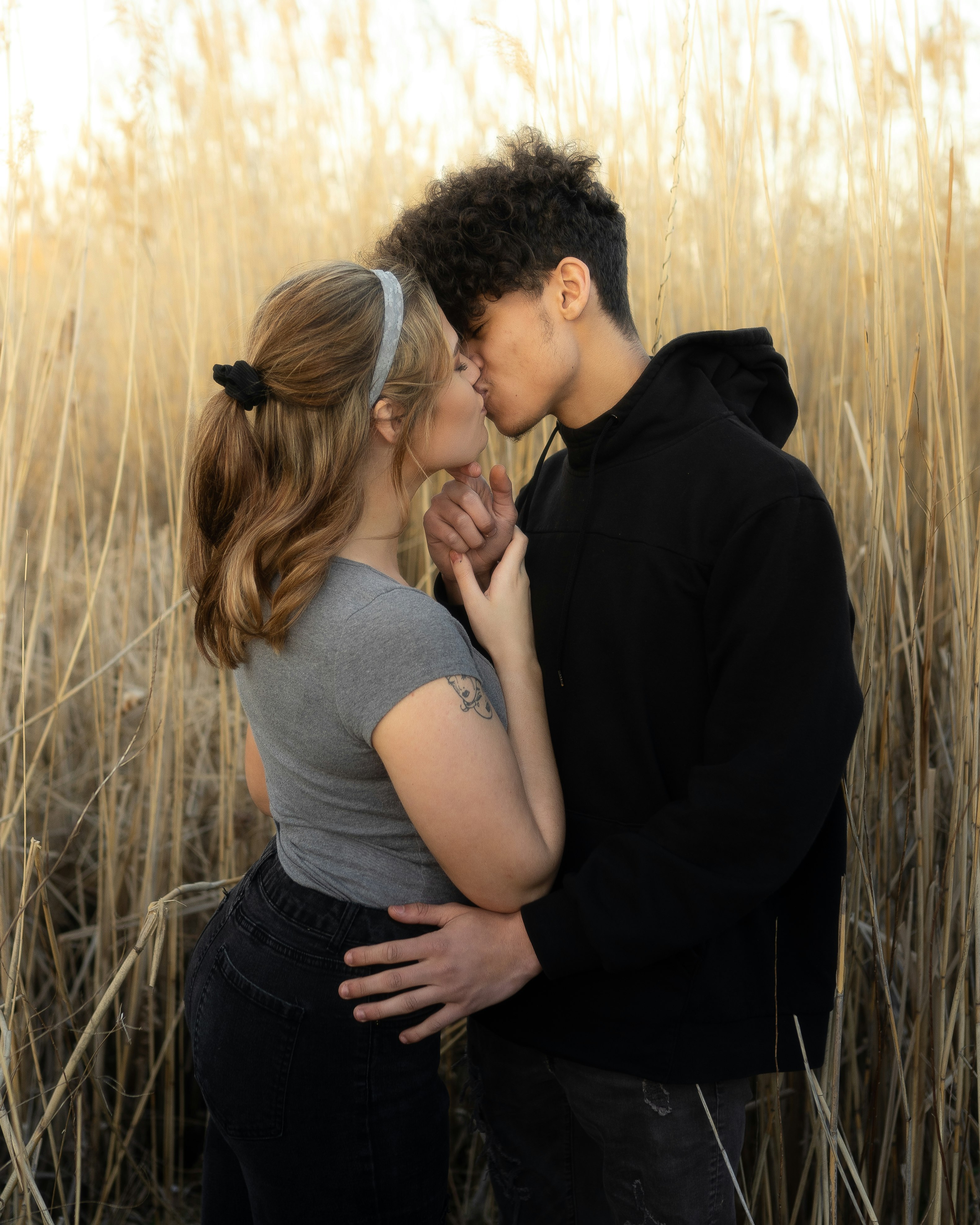 man and woman kissing on brown grass field during daytime