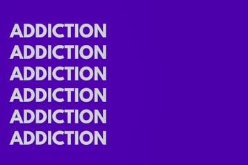 The image features the word 'ADDICTION' repeated six times vertically in bold, white capital letters against a solid purple background.