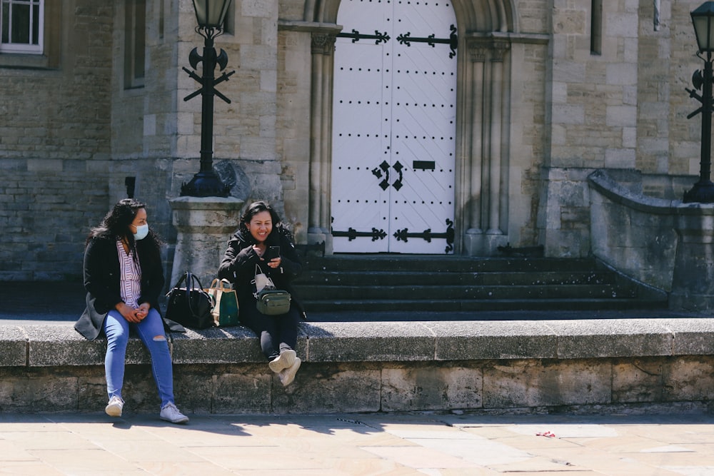 2 women sitting on gray concrete bench