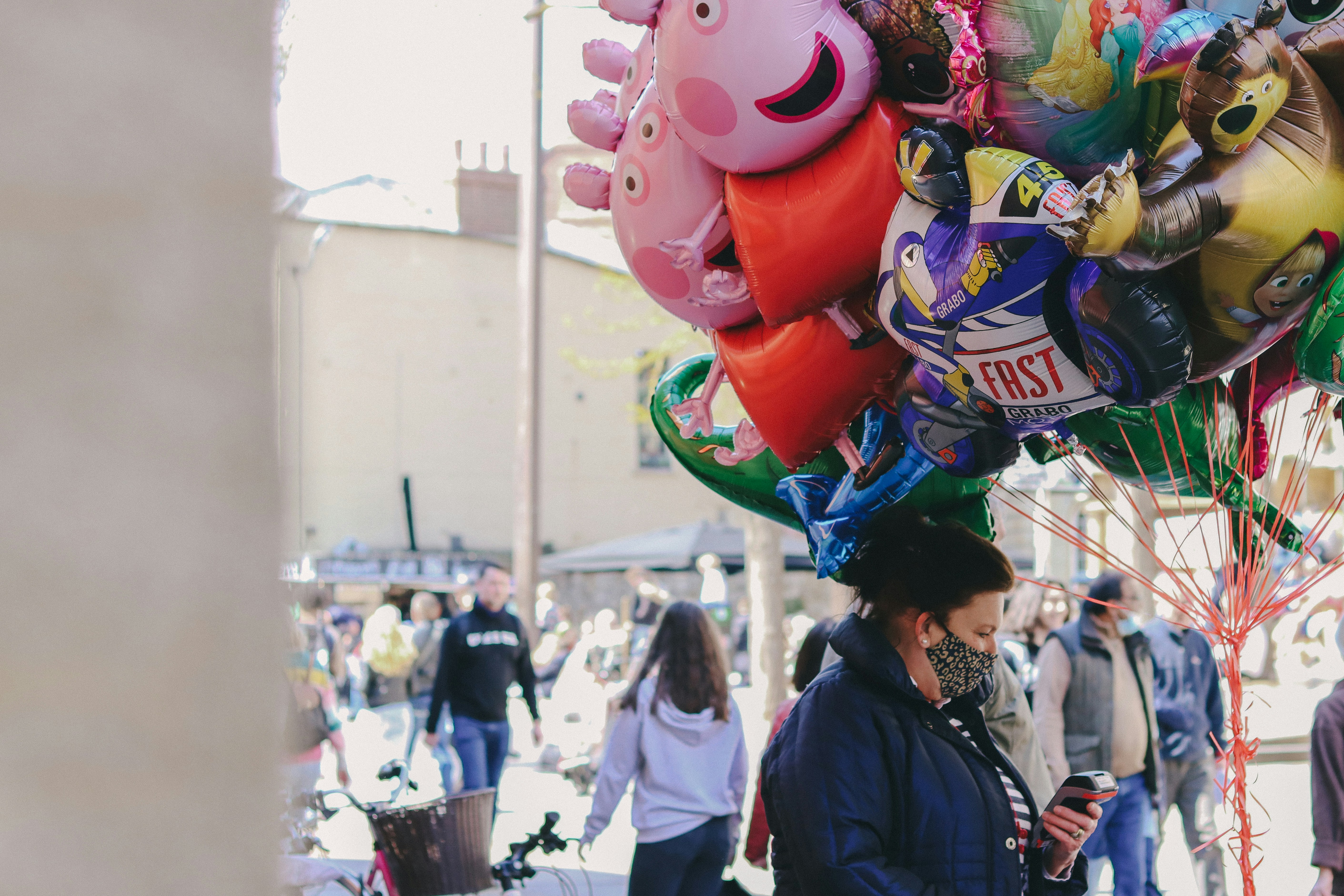 people walking on street with pink and white animal balloon during daytime