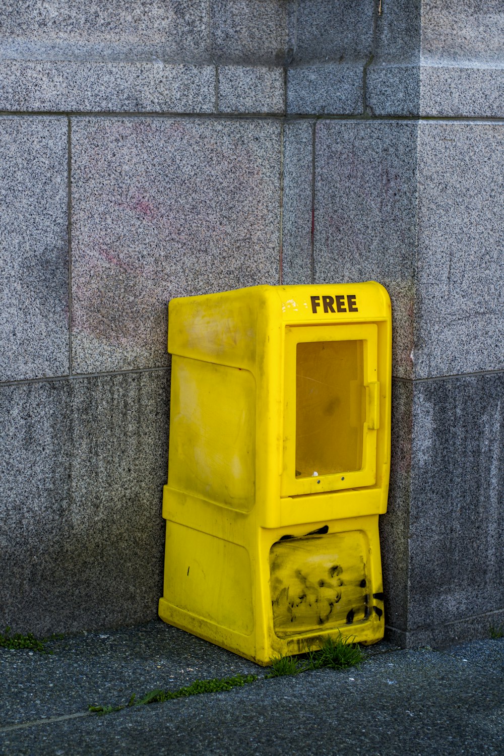 Cubo de basura de plástico amarillo sobre suelo de hormigón gris