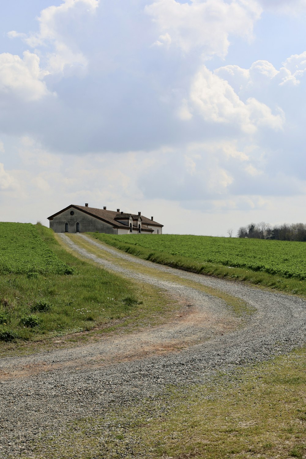 brown wooden house on green grass field under white clouds during daytime