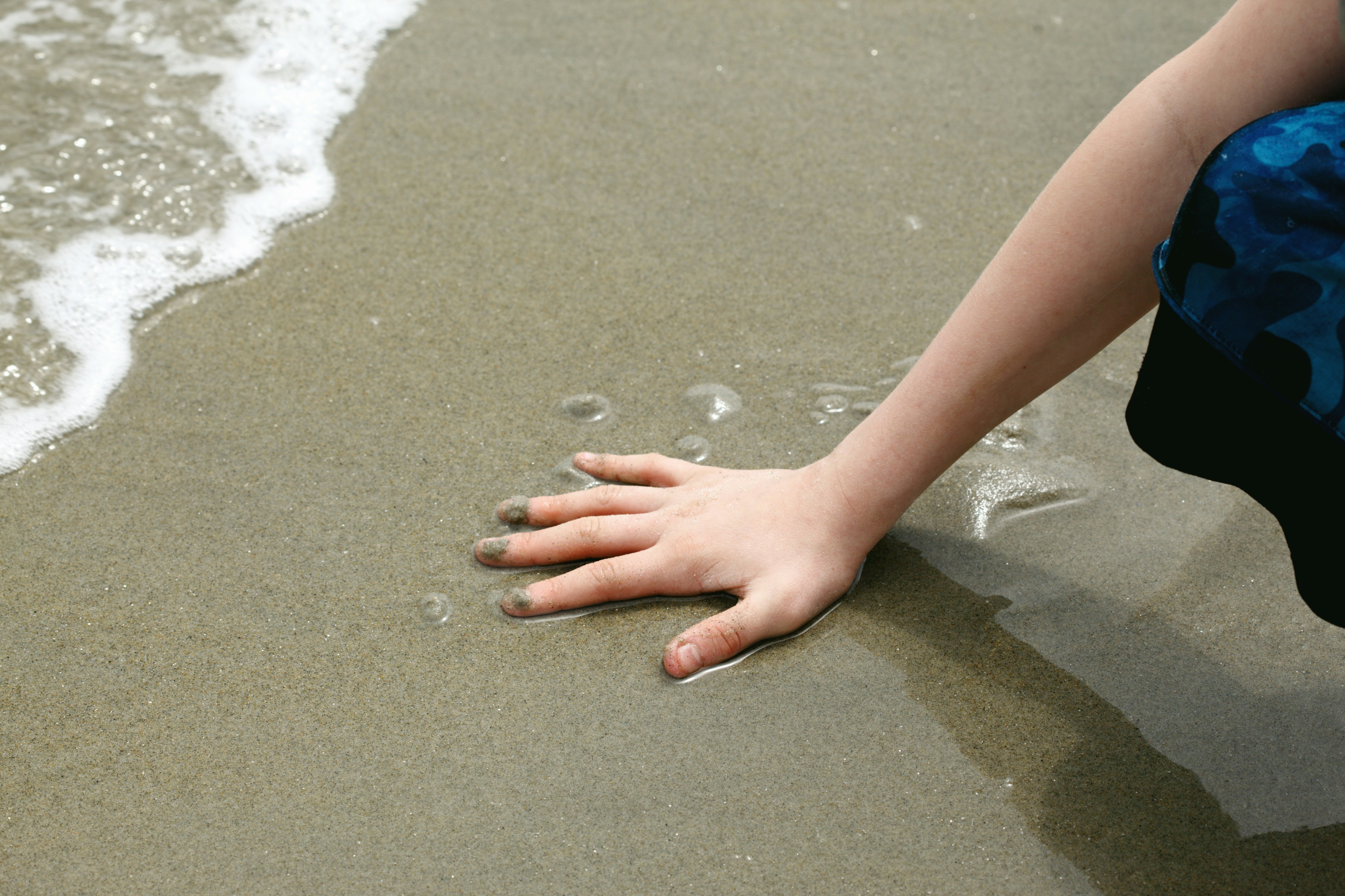 Hand in wet sand. 