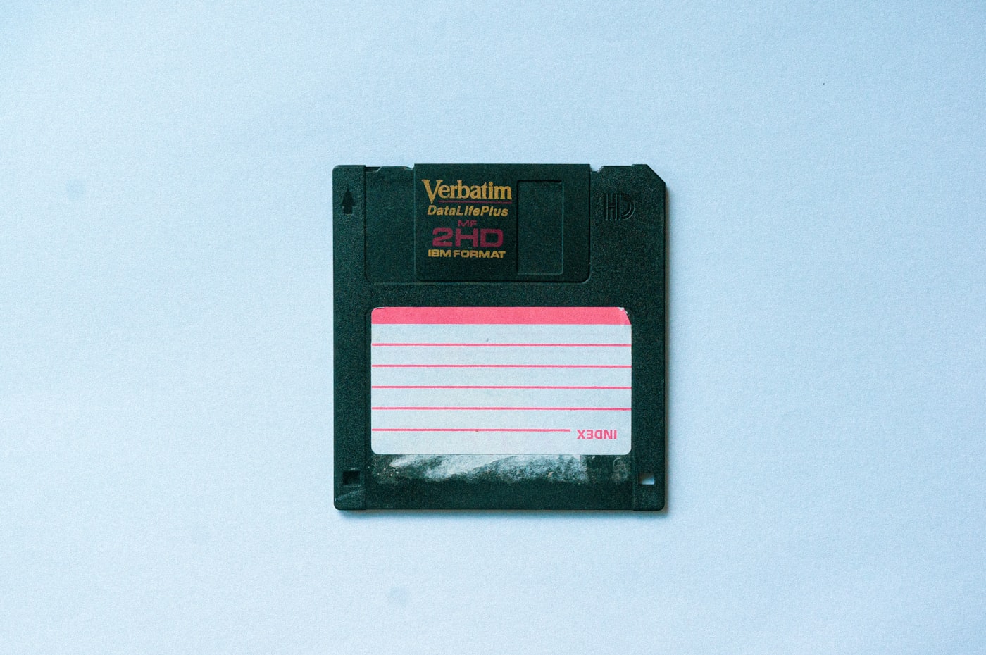 A vintage floppy disk rests beside a smartphone displaying a compact application window.