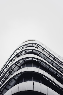 A modern, multi-story building with a sleek, curved design made predominantly of glass and metal. The structure features horizontal lines and minimalistic architecture, creating a futuristic appearance.