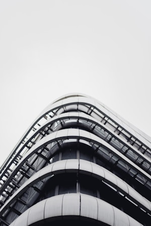 A modern, multi-story building with a sleek, curved design made predominantly of glass and metal. The structure features horizontal lines and minimalistic architecture, creating a futuristic appearance.