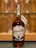 A bottle of Ruddell's Mill Kentucky Straight Bourbon Whiskey is placed on a dark surface with a wooden background. The label indicates it is a crafted small batch, with 46.1% alcohol by volume. Behind the bottle, there are glass shelves with wine glasses.
