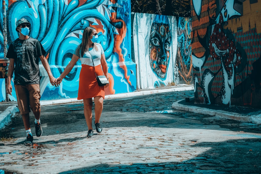 woman in red tank top and blue denim shorts standing on gray concrete pavement