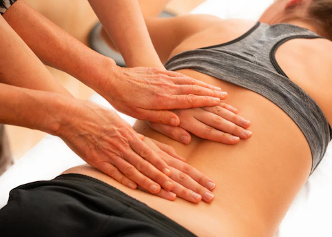 Muscle therapy in action for back pain on a woman lying in prone position