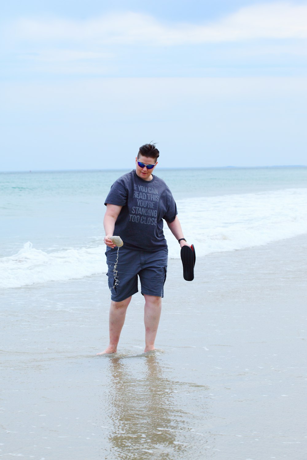 회색 크루넥 티셔츠를 입고 검은색 반바지를 입은 남자가 낮 동안 해변에서 뛰고 있다