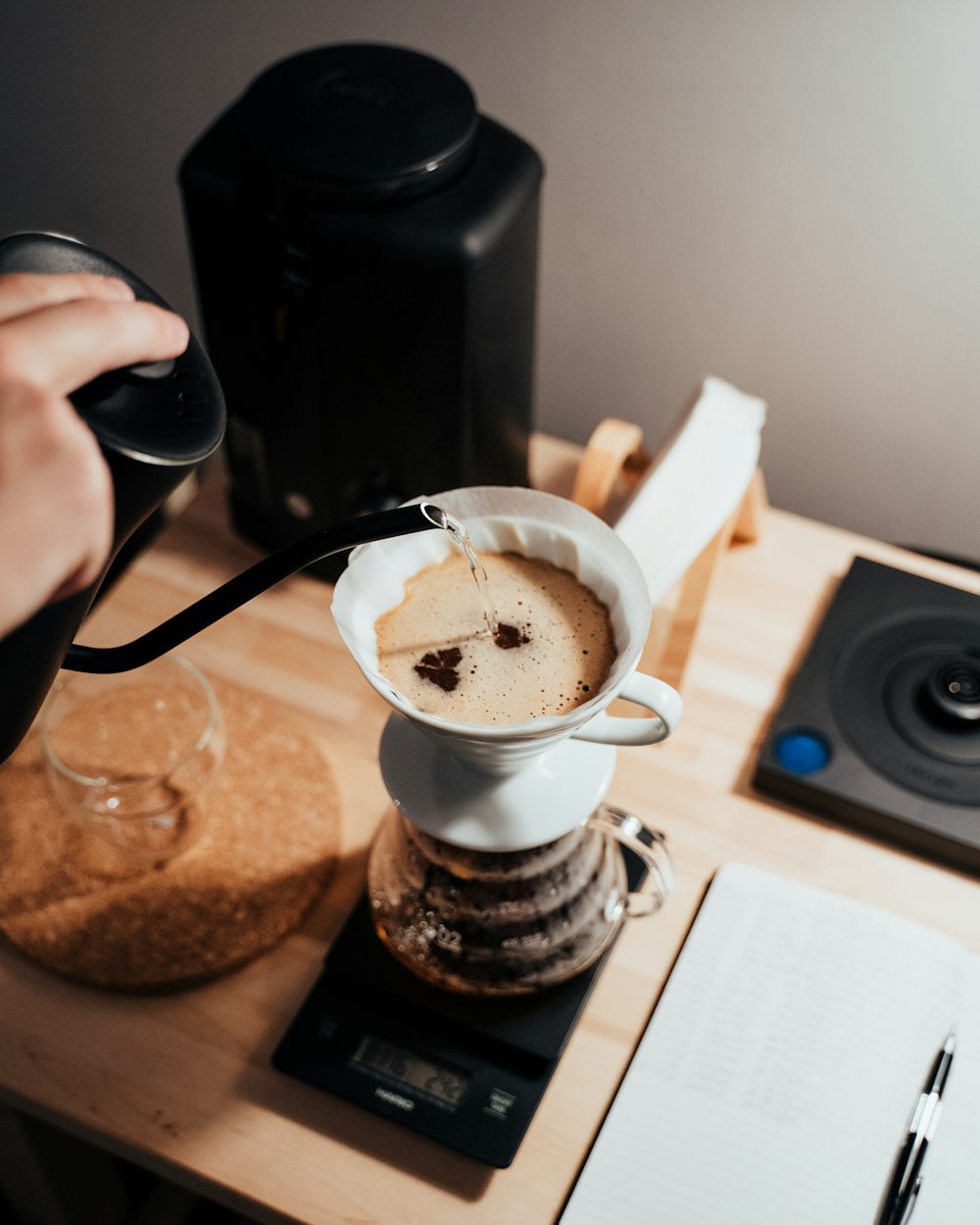 白い陶器のマグカップにコーヒーを注ぐ人