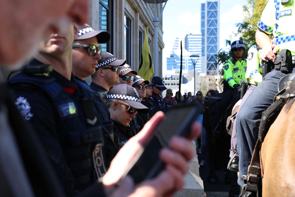 검은 경찰 유니폼을 입은 남자가 검은 스마트폰을 들고 있다