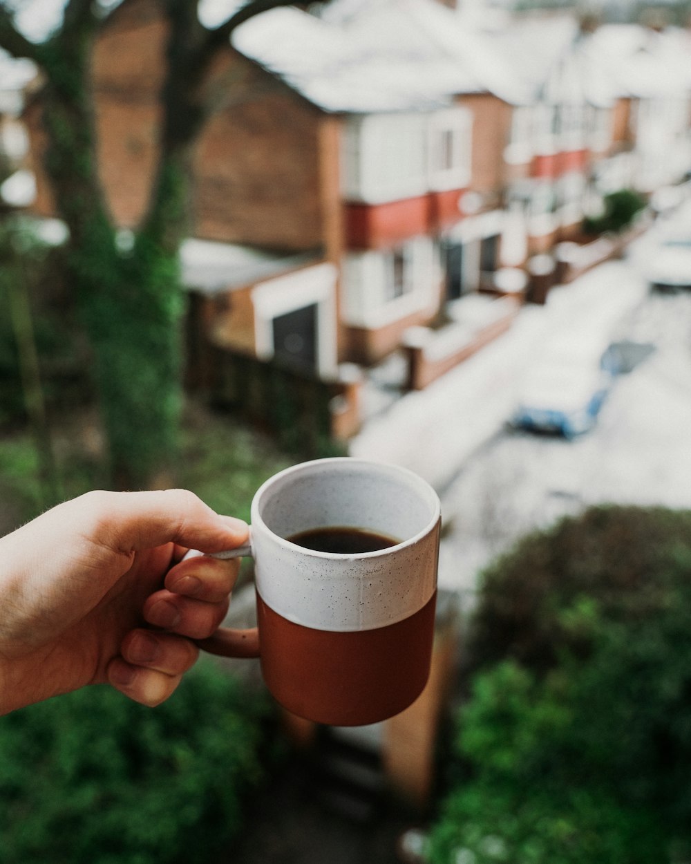 person holding orange and white ceramic mug