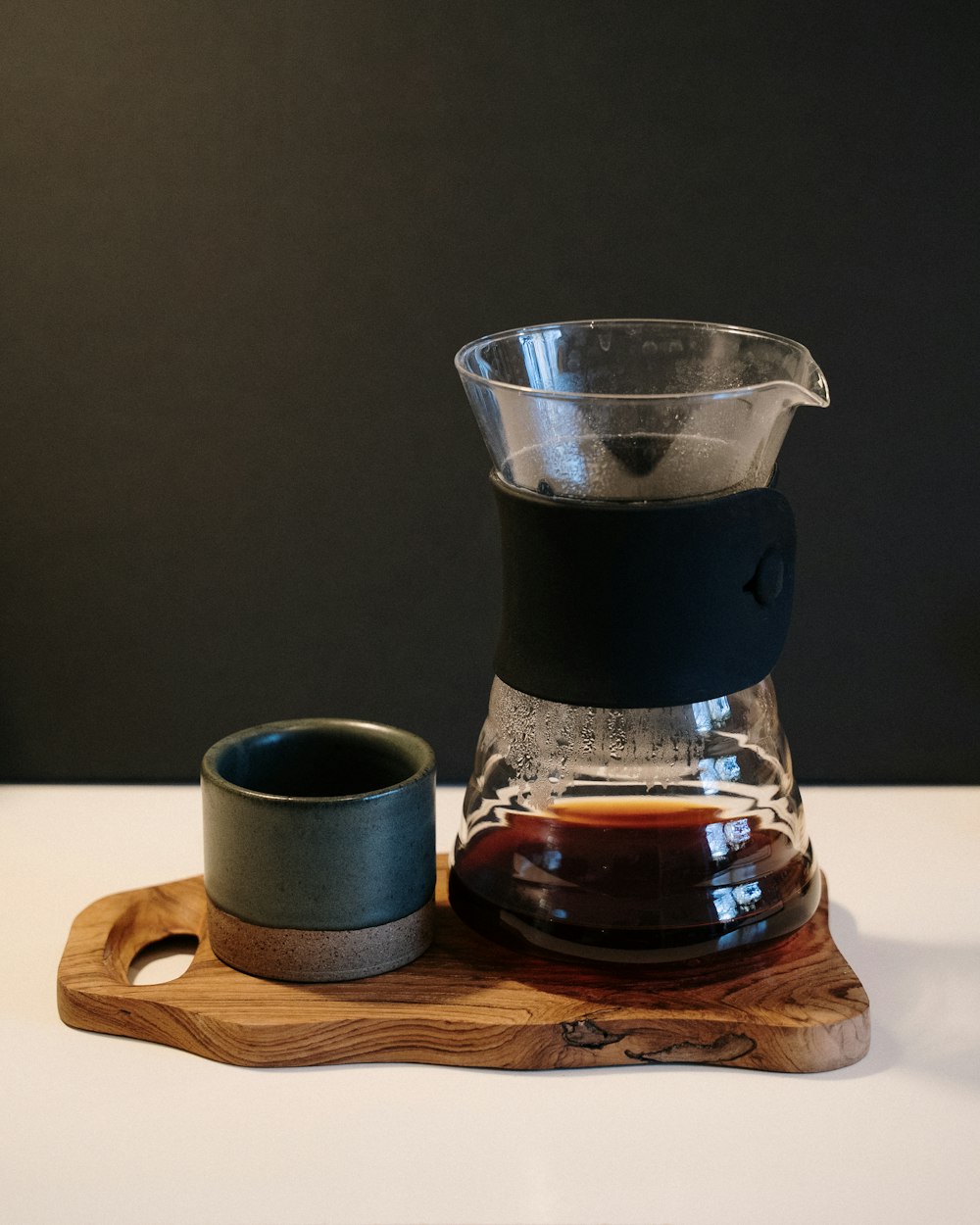 black coffee in clear glass pitcher on brown wooden coaster