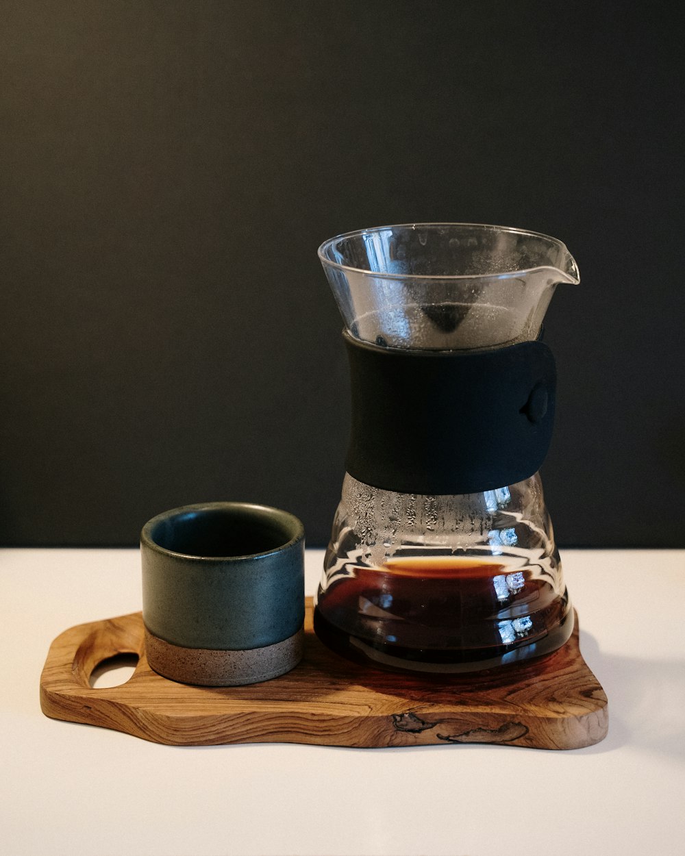 茶色の木製コースターに透明なガラスのピッチャーに入ったブラックコーヒー