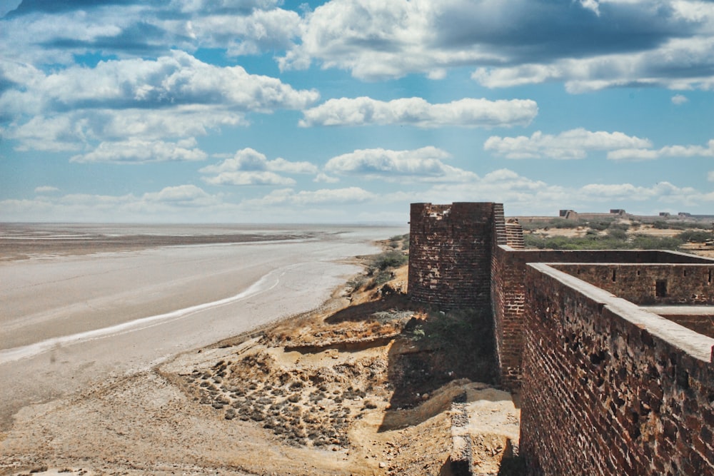 Pared de ladrillo marrón en la playa durante el día