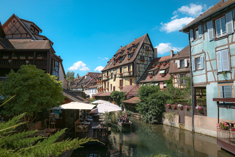 Maisons en béton brun et blanc près de la rivière sous le ciel bleu pendant la journée