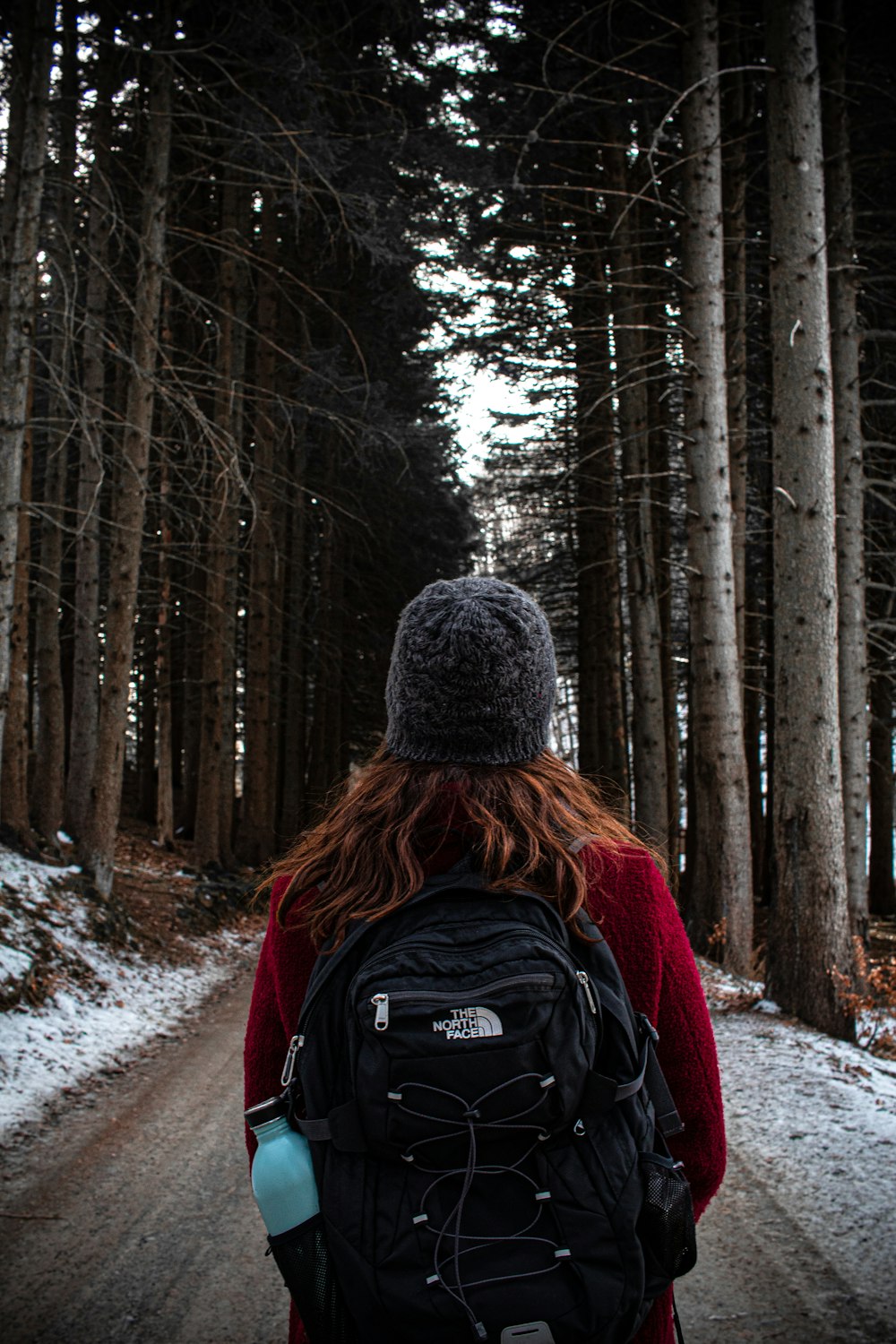 person in black knit cap and red jacket standing on snow covered ground