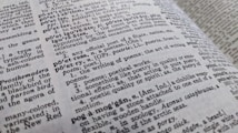 A close-up view of an open dictionary showing definitions related to poetry. The text is in black and white, with some words bolded for emphasis. The page curvature is slightly visible, indicating the book is laid open at an angle.