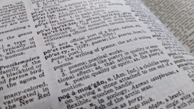 A close-up view of an open dictionary showing definitions related to poetry. The text is in black and white, with some words bolded for emphasis. The page curvature is slightly visible, indicating the book is laid open at an angle.