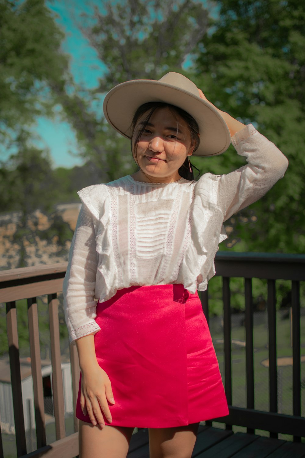 Ragazza in camicia bianca a maniche lunghe e gonna rossa che indossa un cappello da cowboy marrone