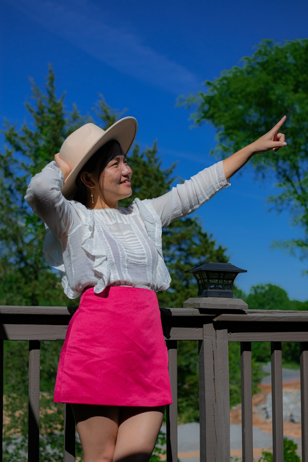 Mujer con camisa blanca de manga larga y pantalones rosas con sombrero marrón