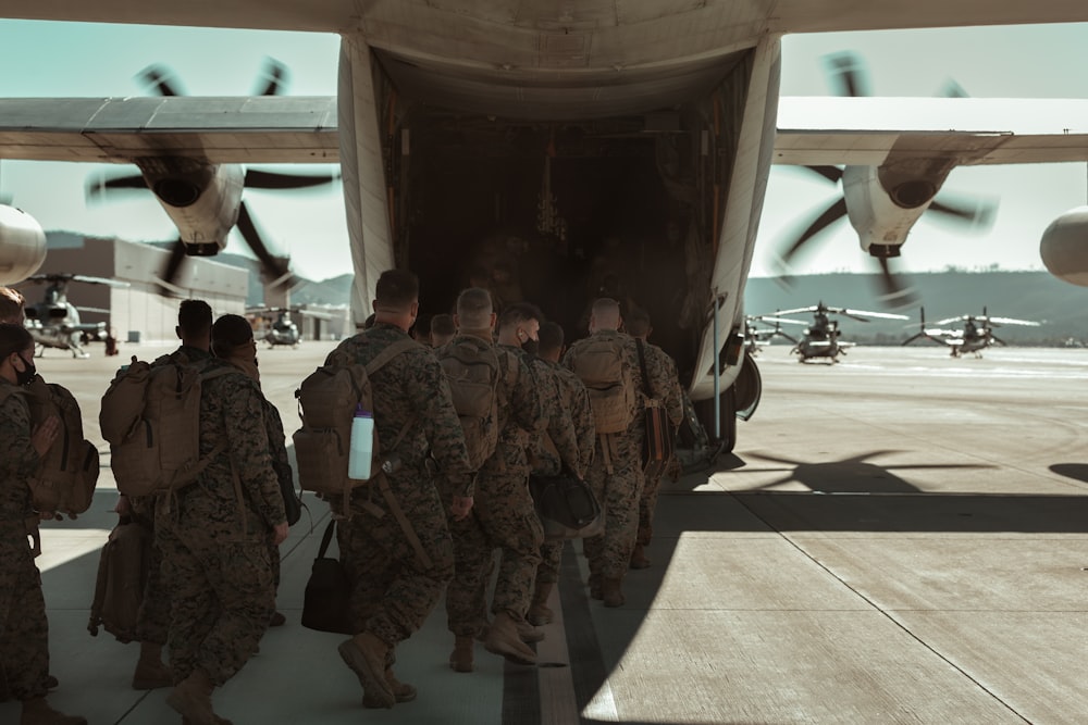 group of men in camouflage uniform standing near white airplane