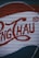 A section of a corrugated metal surface is painted with large red letters and a distinct logo design, possibly resembling vintage signage or advertising artwork.