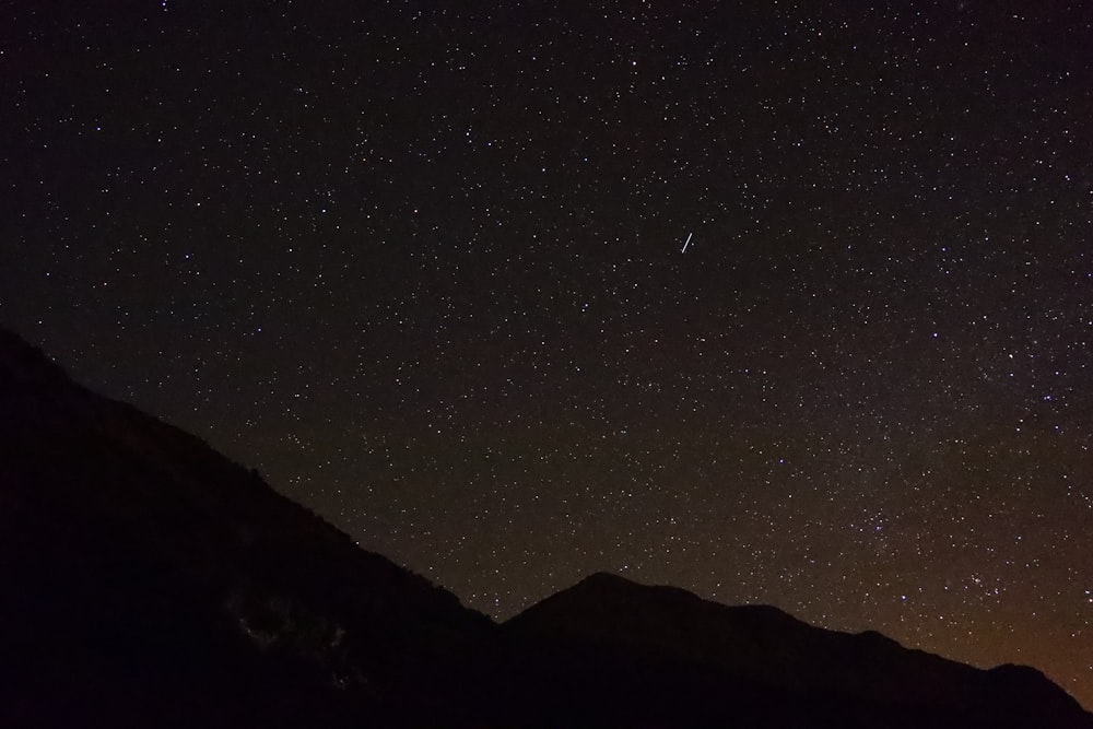 silhouette of mountain under starry night