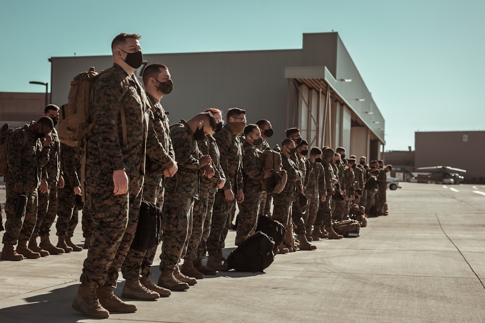 homens em uniforme de camuflagem preto e marrom em pé no chão marrom