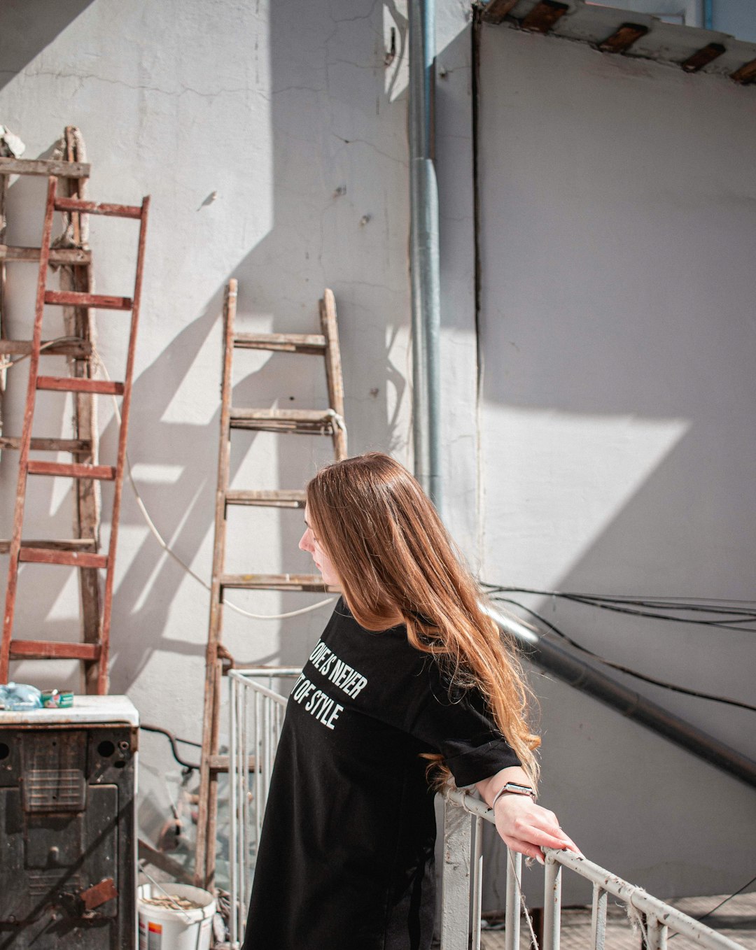 woman in black and white crew neck t-shirt standing near red metal ladder